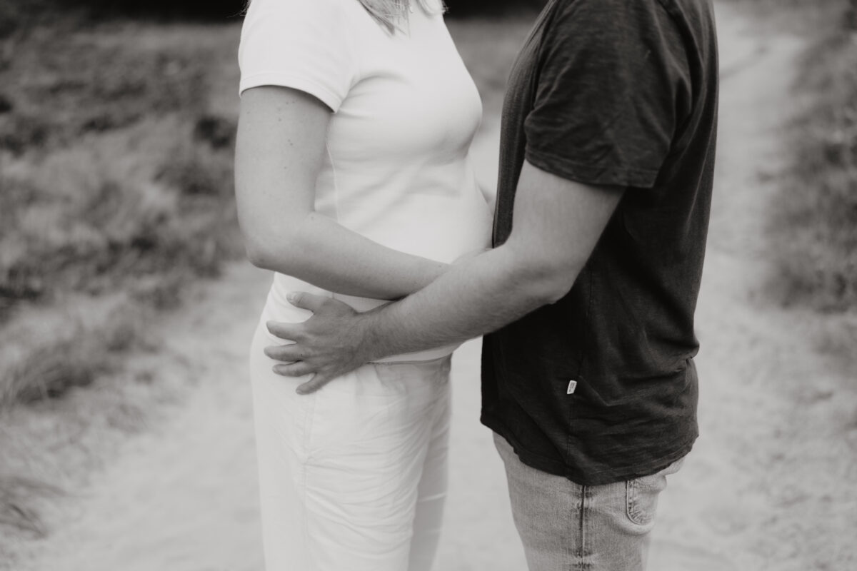 Babybauch Fotografie Portfolio Paar umarmt sich Outdoor Schwarz-Weiß-Fotografie