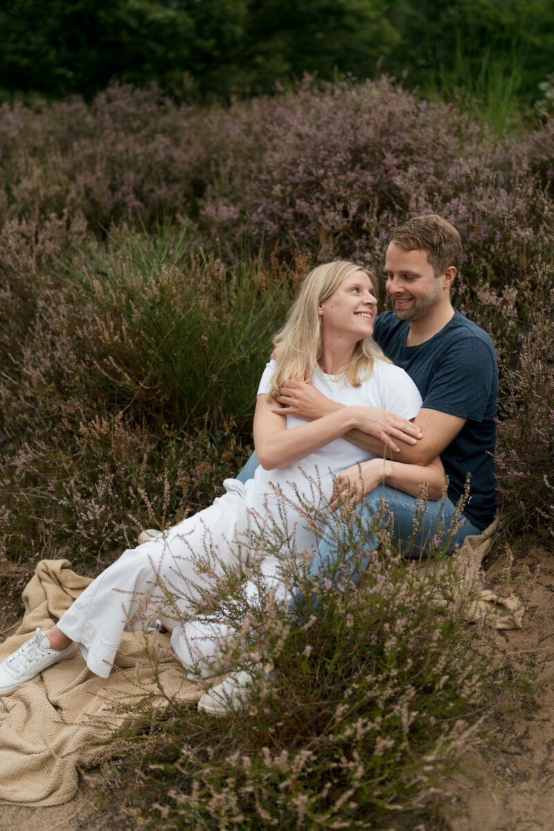 Babybauch Fotografie Portfolio junges glückliches Paar sitzt in der Natur