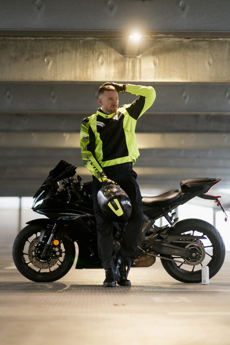 Portraitfoto eines Mannes in Motorrad Kleidung, im gehen fotografiert