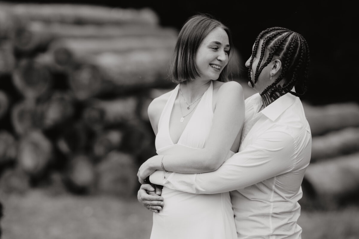 Sie wird von hinten umarmt und lächelt, fotografiert in Schwarz-Weiß