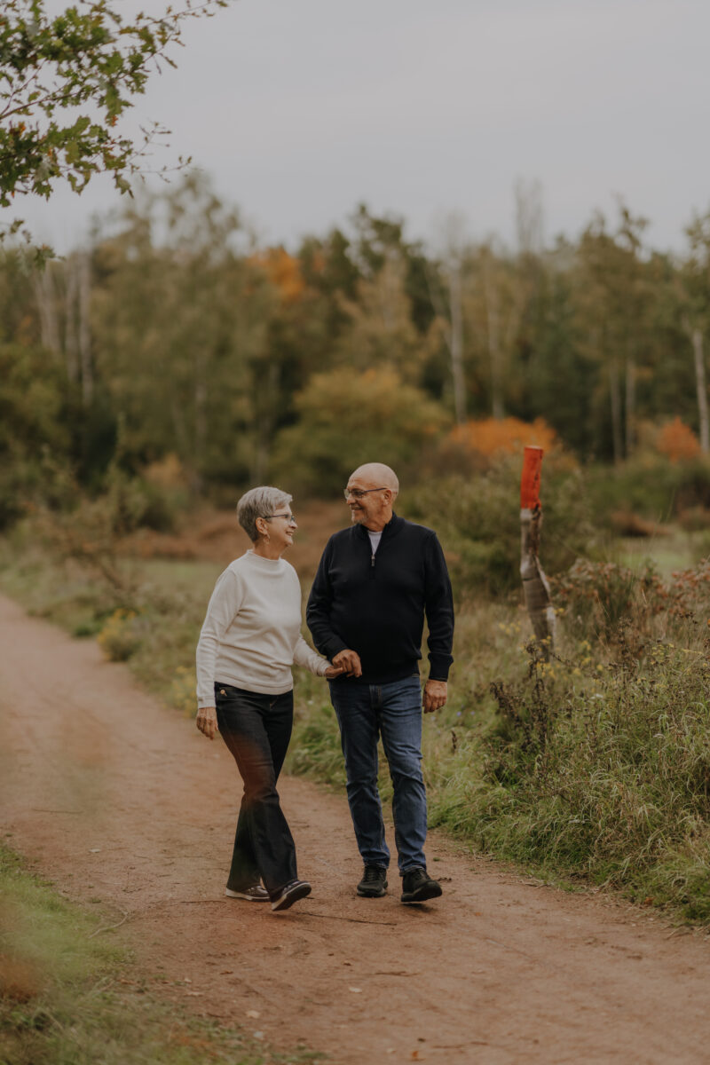 Paar läuft Händchen haltend auf die Kamera zu und schauen sich an