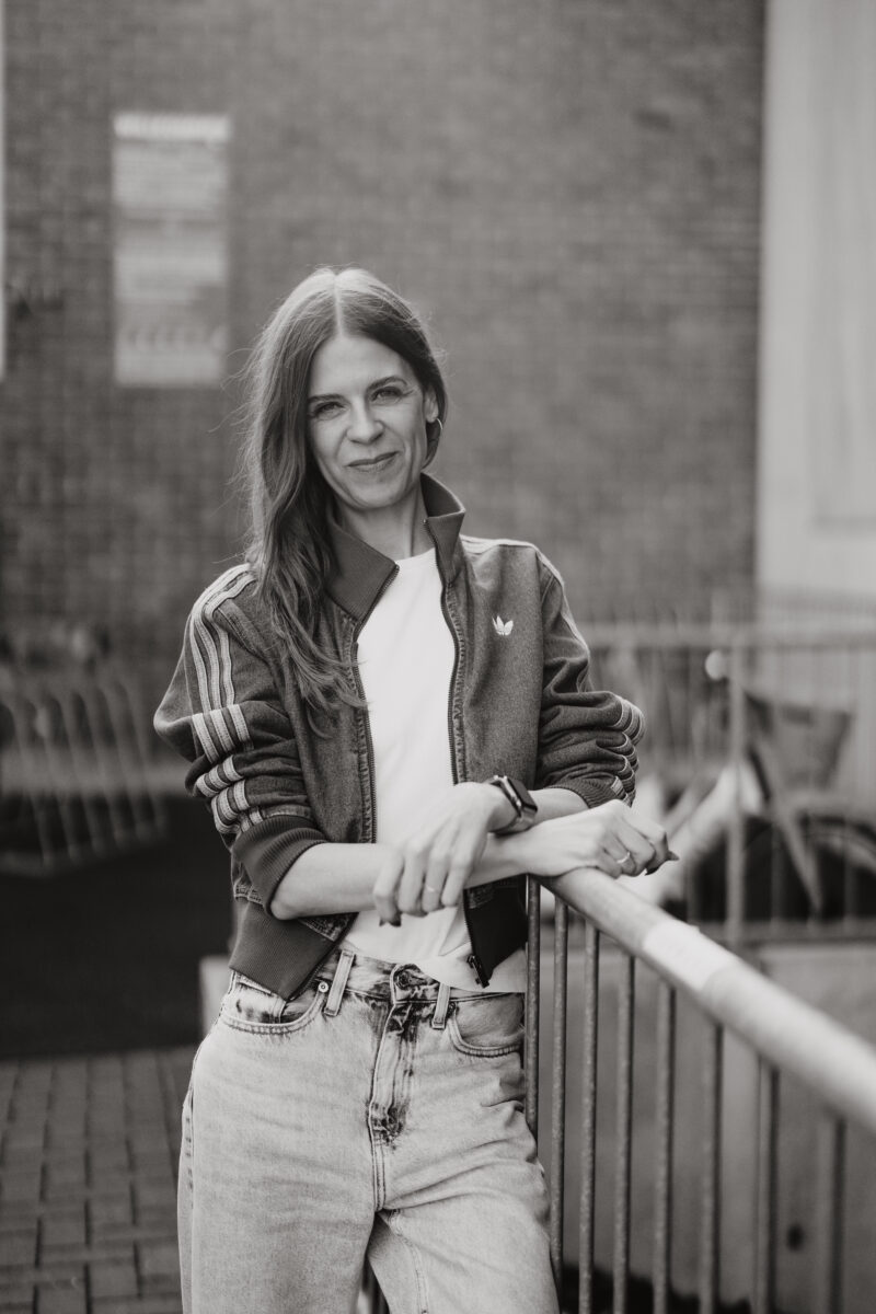 Schwarz-Weiß Portraitfoto einer Frau, an einem Geländer lehnend