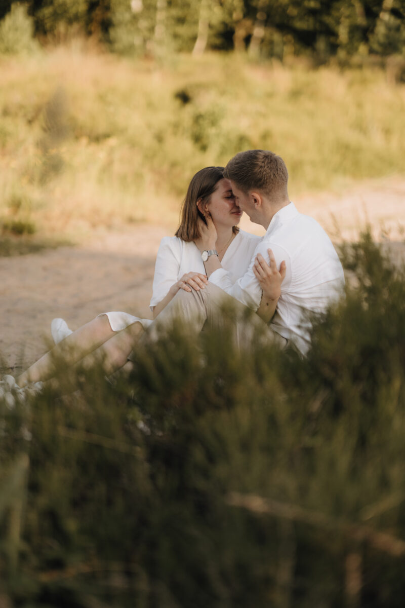 Paar sitzt Arm in Arm und setzt zum Kuss an