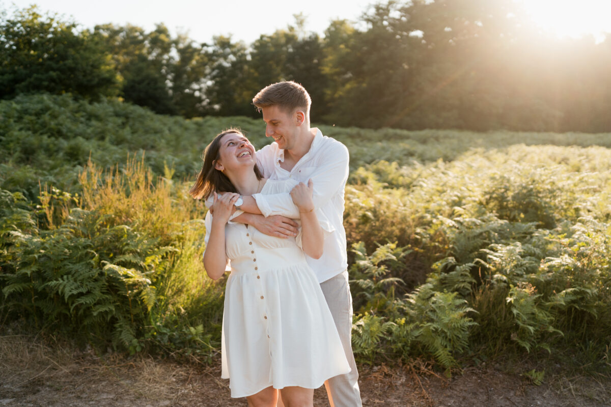 Paar tanzt in der Abendsonne auf einem Feld und lacht