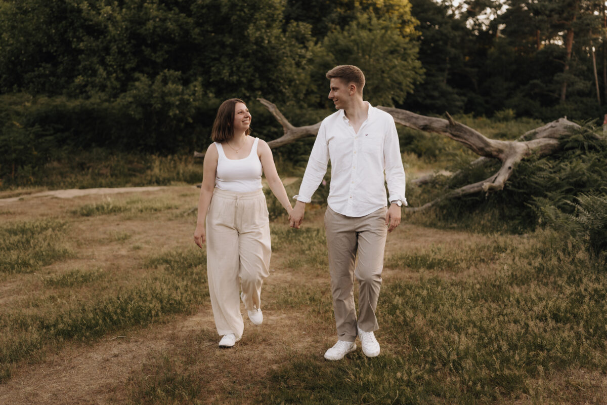 Paar geht Händchen haltend über eine Wiese und schaut sich an