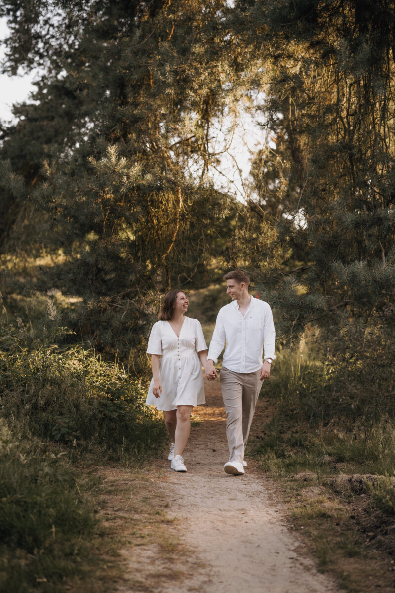 Paar geht Händchen haltend durch den Wald und schaut sich an