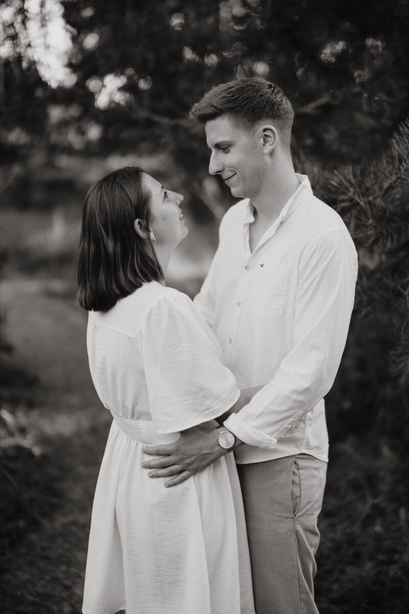 Paar schaut sich lächelnd in die Augen und setzt zum Kuss an, fotografiert in Schwarz-Weiß