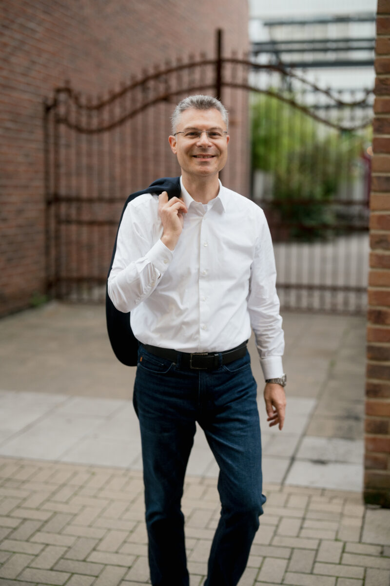 Portraitfoto eines Mannes im Business Look vor einem Tor