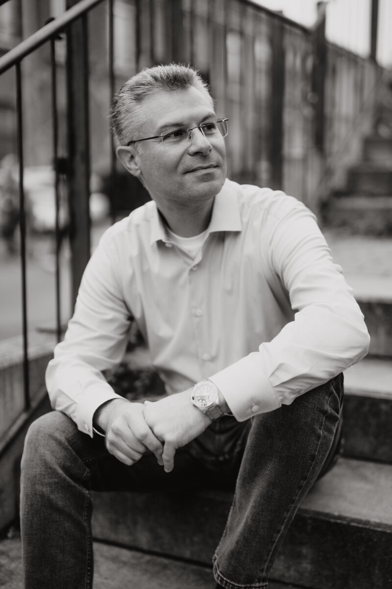 Schwarz-Weiß Portraitfoto eines Mannes auf der Treppe sitzend