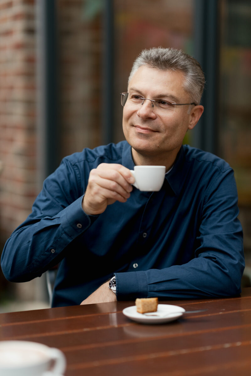 Portraitfoto eines Mannes, sitzend im Café mit Espresso Tasse in der Hand