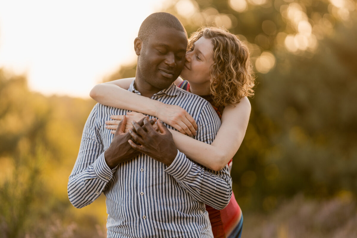 Sie umarmt ihn von hinten und küsst seine Wange