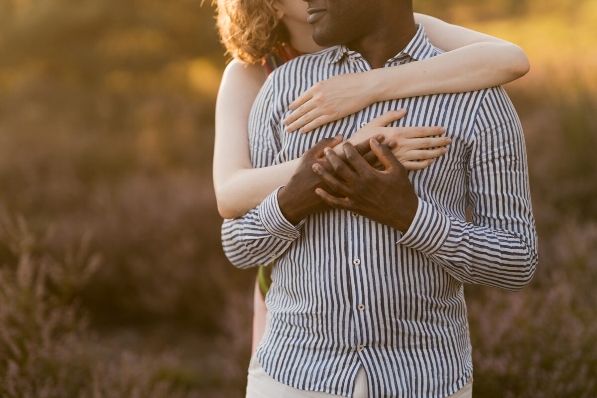 Sie umarmt ihn von hinten und gibt ihm einen Stirnkuss