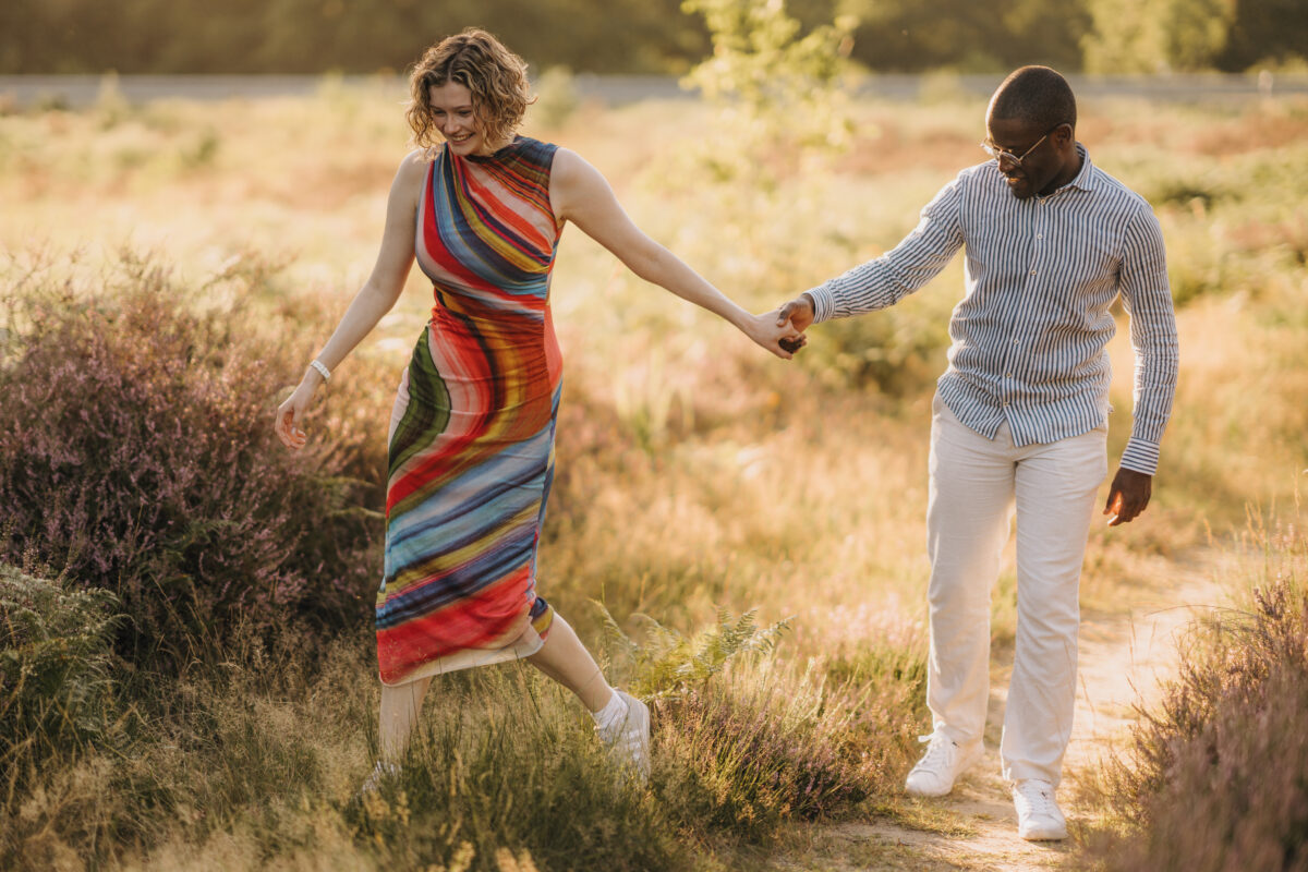 Paar schlendert in der Abendsonne auf einer Wiese