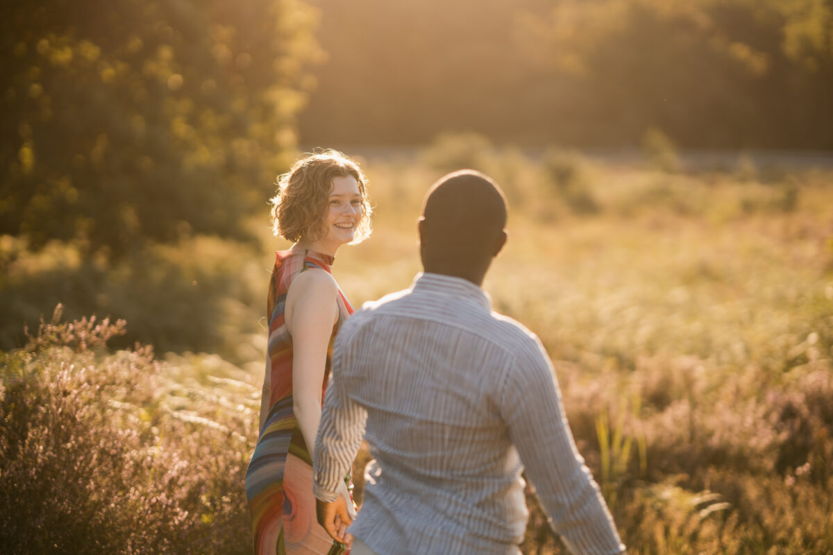 Paar schlendert Händchen haltend in denSonnenuntergang