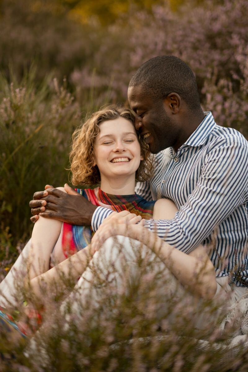 Paar liegt lachend, Arm in Arm auf einer Wiese