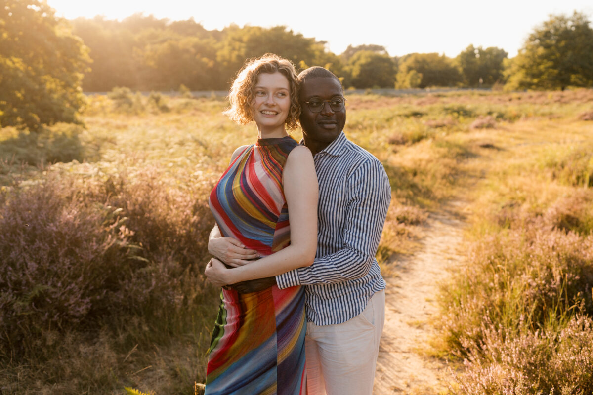 sie wird in der Abendsonne von hinten umarmt und lächelt