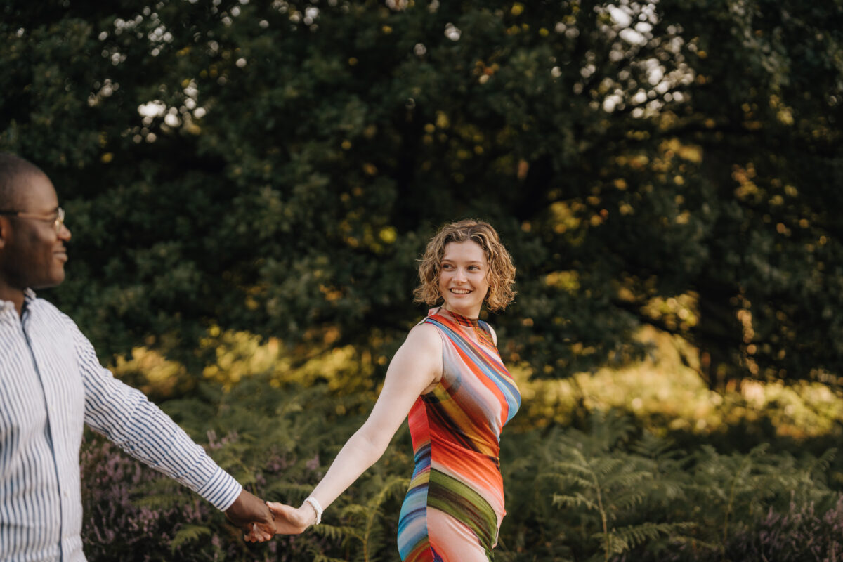 Paar schlendert durch den Wald, schaut sich lächelnd an