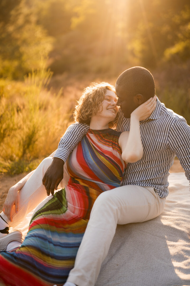 Paar liegt in der Abendsonne auf einer Decke und setzt zum Kuss an