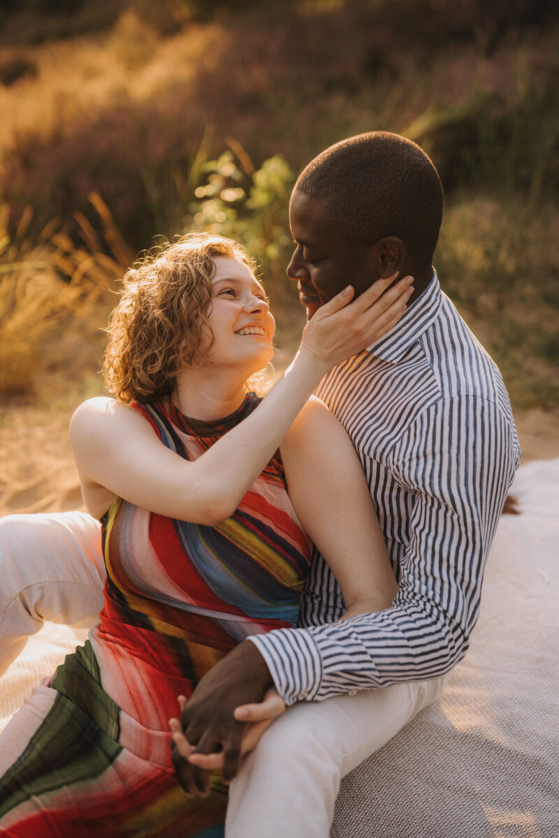 Paar liegt auf einer Wiese im Sonnenuntergang und setzt zum Kuss an