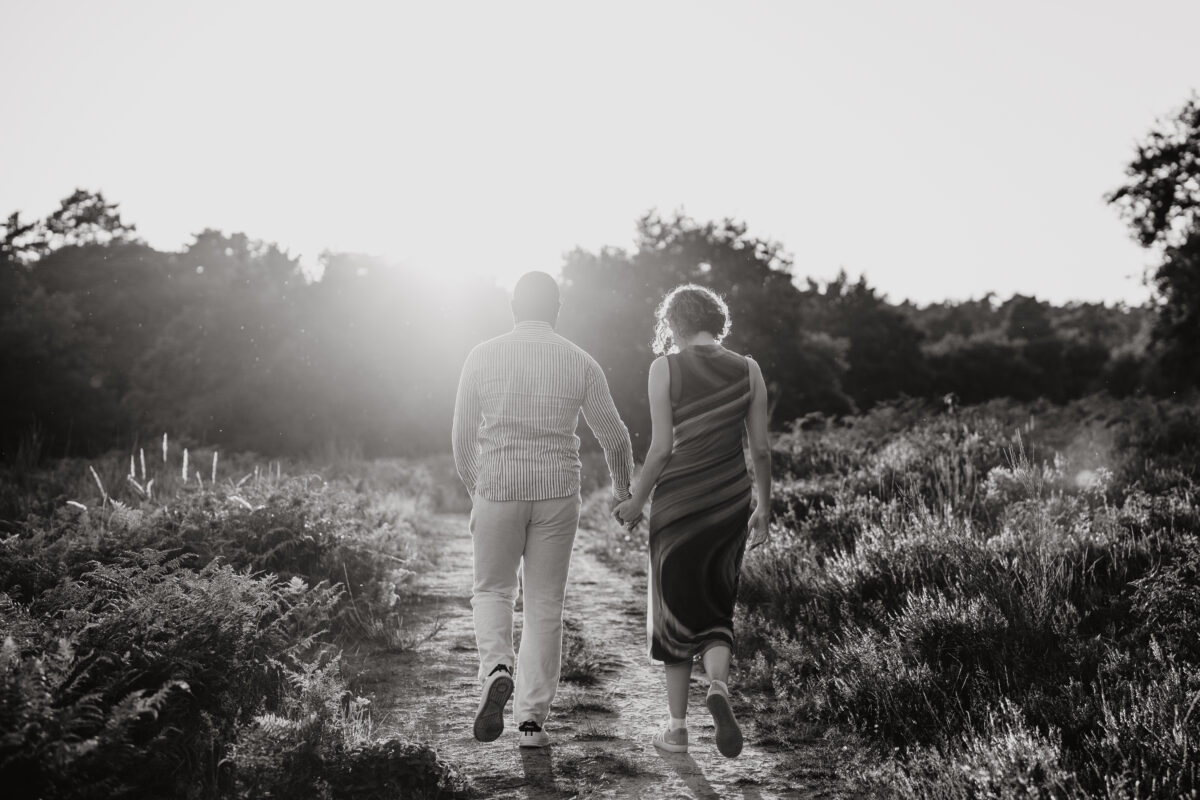Paar schlendert Händchen haltend in die Abendsonne, fotografiert in Schwarz-Weiß