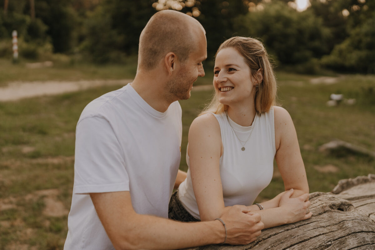 Paar schaut sich auf einen Ast gelehnt, verliebt in die Augen