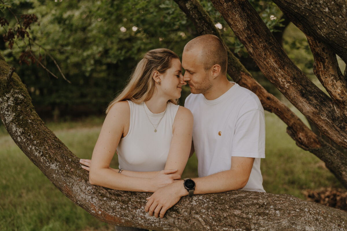 Paar lehnt auf einem Baum und setzt zum Kuss an