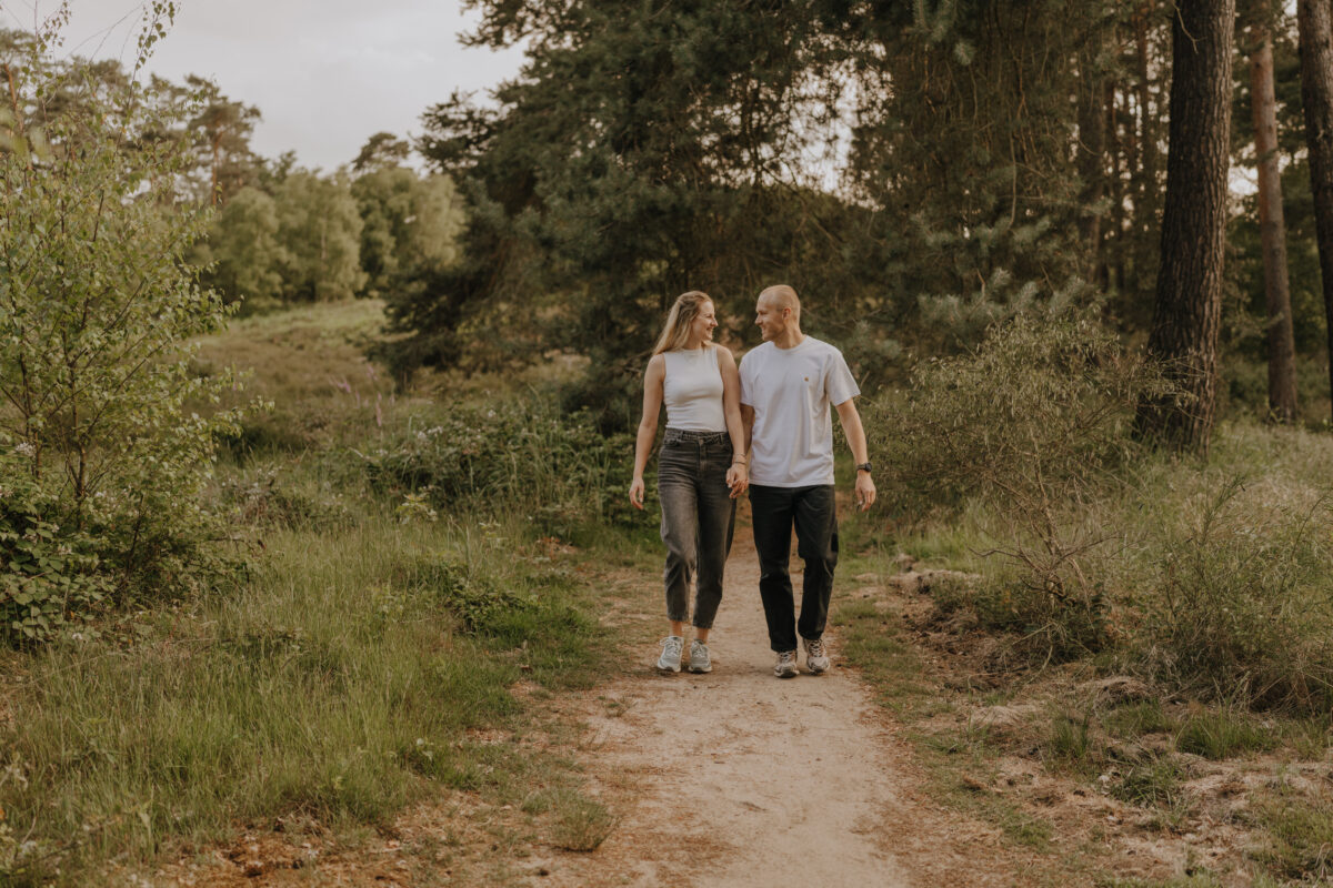 Paar spaziert Händchen haltend über eine Wiese und schaut sich an