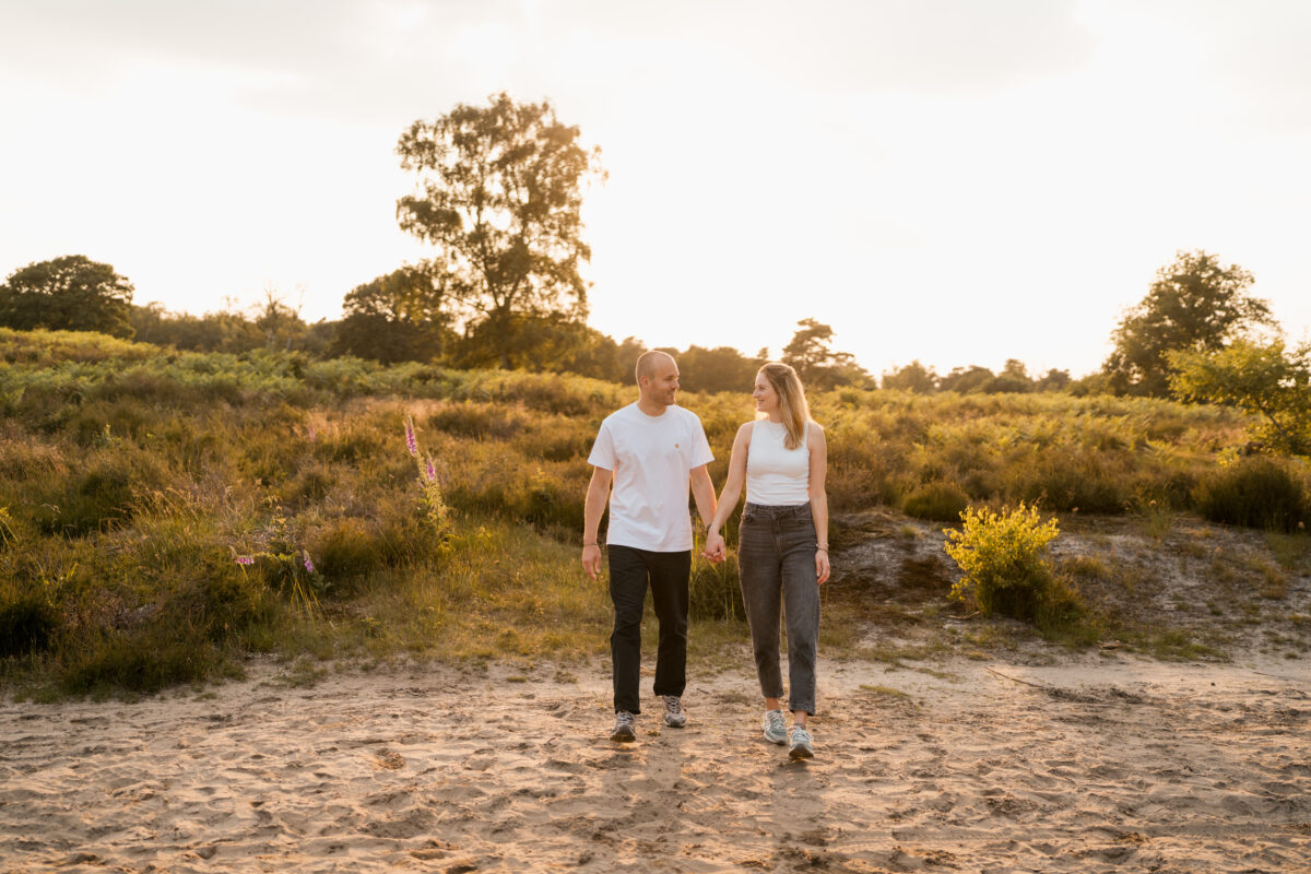 Paar schlendert in der Abendsonne Händchen haltend auf die Kamera zu