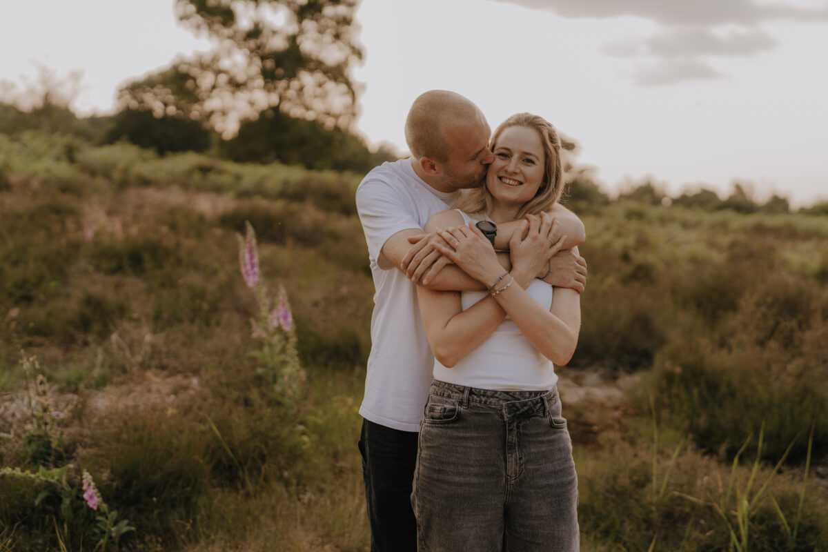 Er umarmt sie von hinten und küsst sie auf die Wange