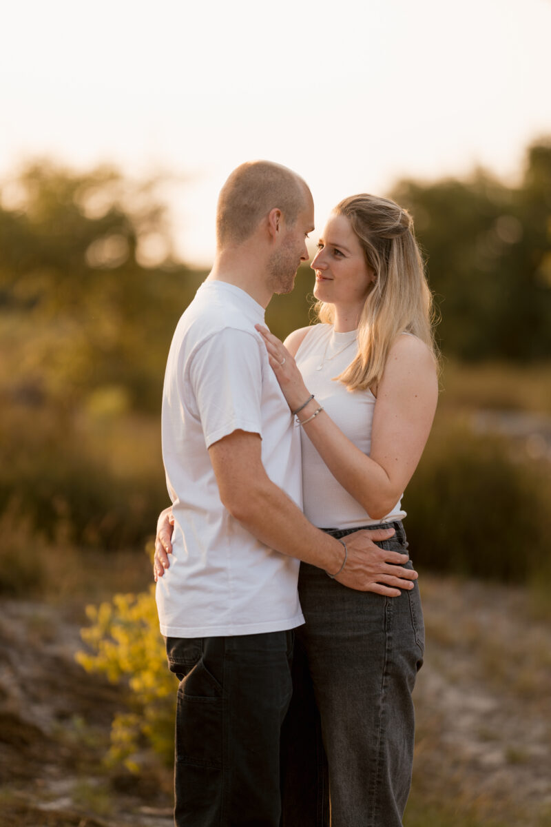 Paar hält sich im Sonnenuntergang in den Armen und schaut sich verliebt an