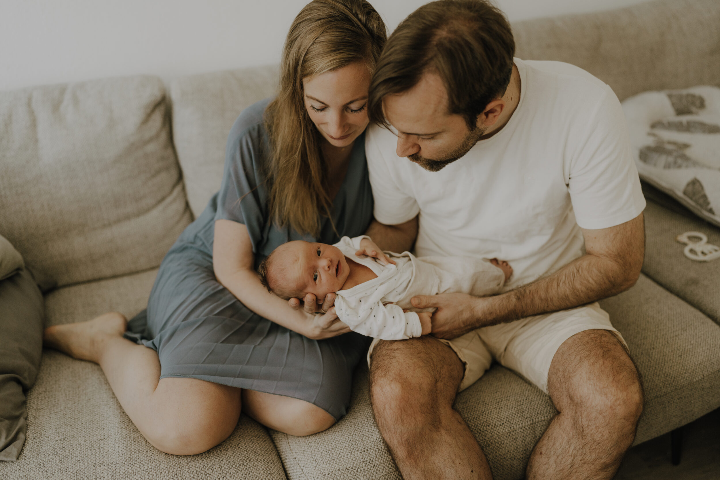 Newborn Portfolio Eltern mit Baby im Arm auf der Couch sitzend