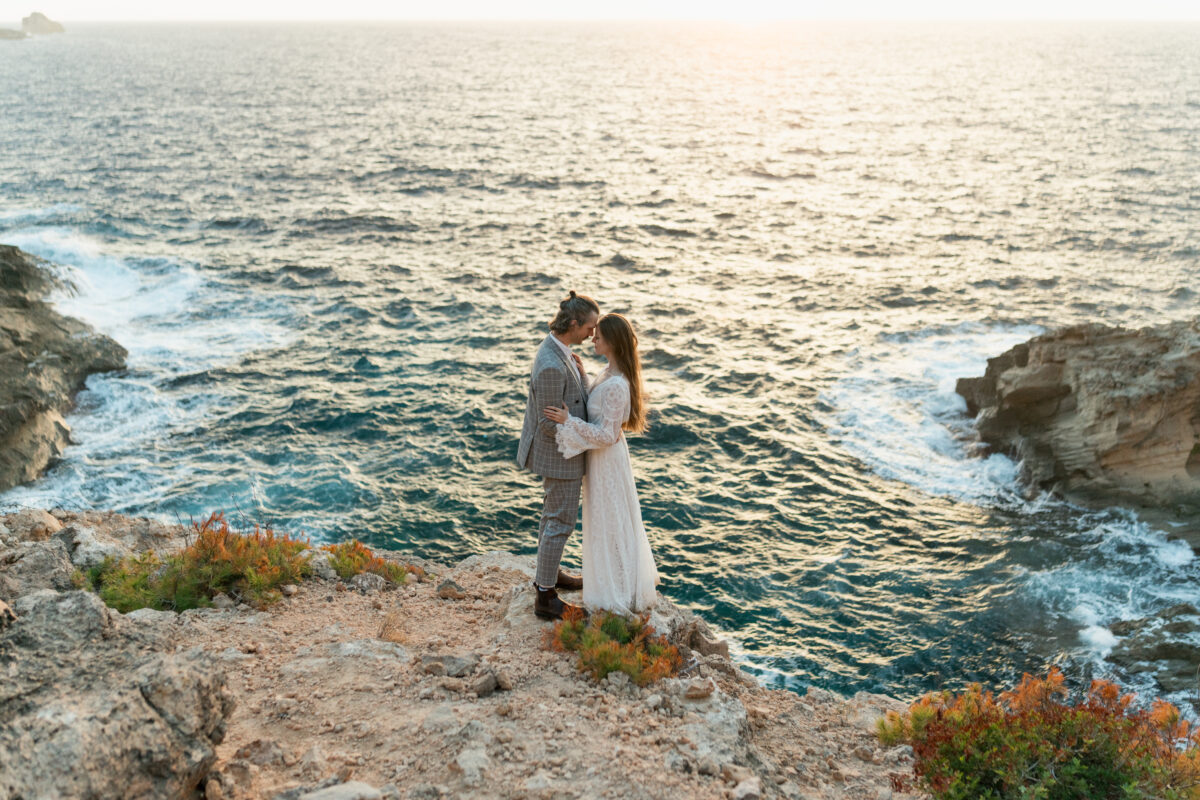 Hochzeitsportfolio, Braut und Bräutigam stehen eng beieinander, im Hintergrund Wasser