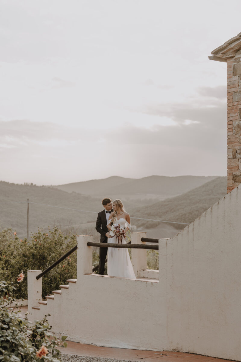 Destination Wedding Portfolio Hochzeitspaar Arm in Arm auf einer Treppe mit Naturkulisse im Hintergrund