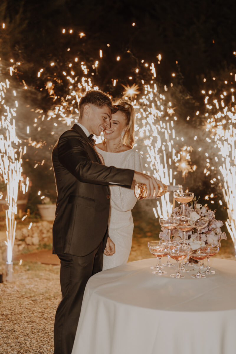Destination Wedding Portfolio Hochzeitspaar gießt Getränke vor Feuerwerk ein