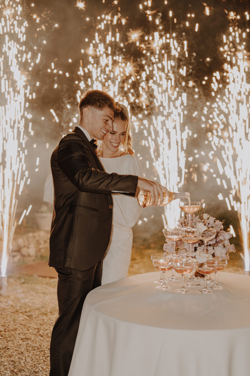 Destination Wedding Portfolio Hochzeitspaar gießt Getränke vor Feuerwerk ein