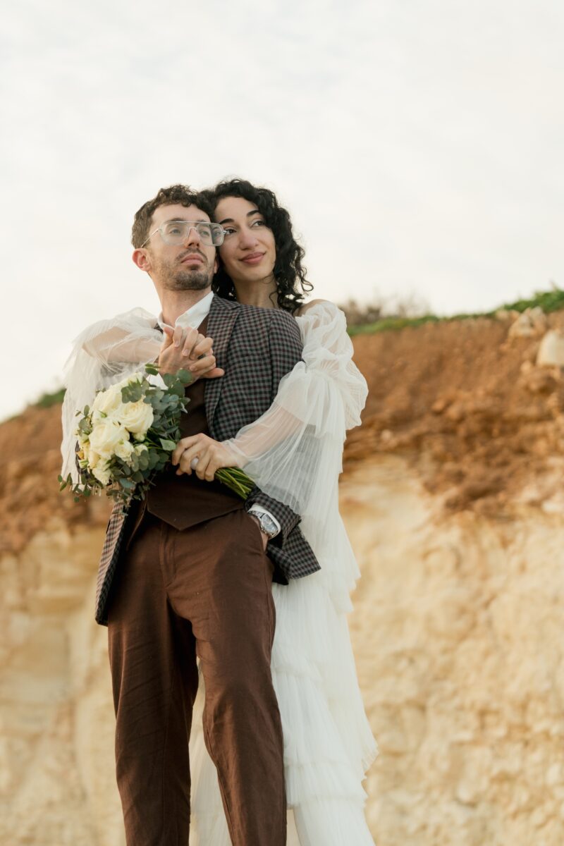 After Wedding, Braut umarmt ihren Mann von hinten.