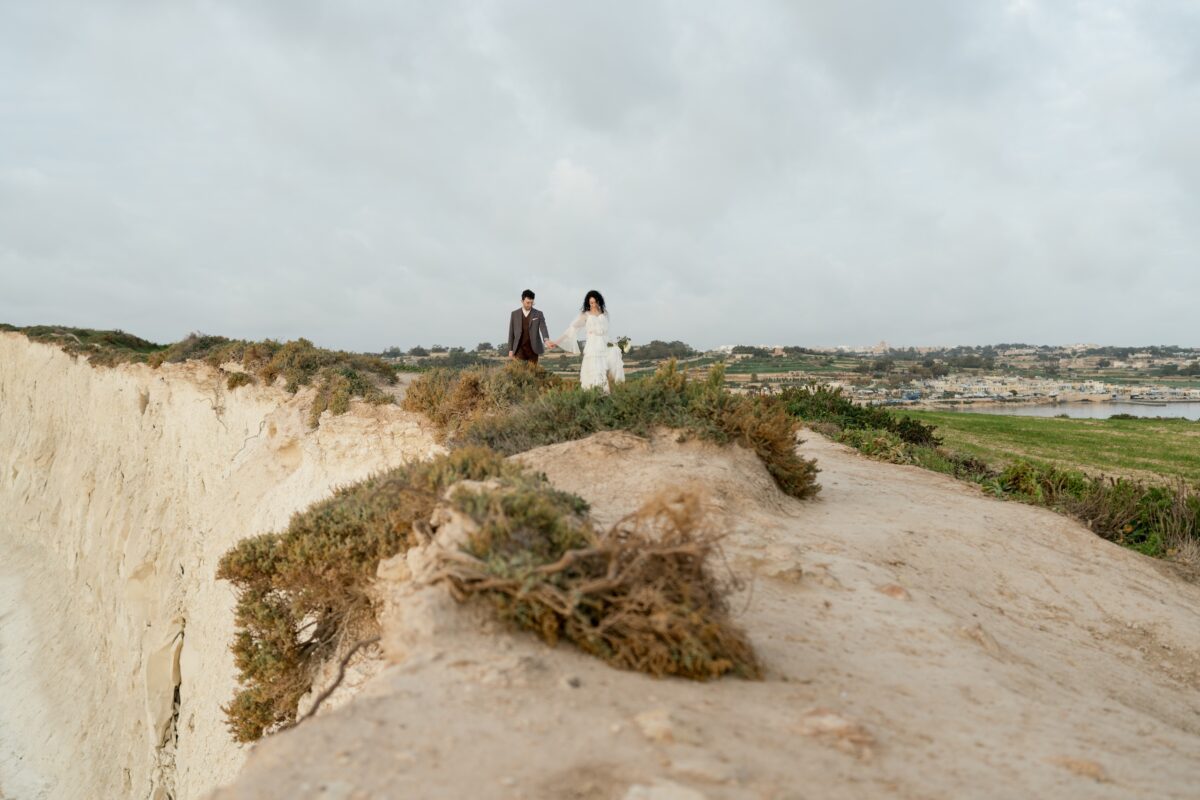 After Wedding, Totale, Braut und Bräutigam laufen zusammen nach vorne, beide Blicken auf den Boden und halten ihre Hände