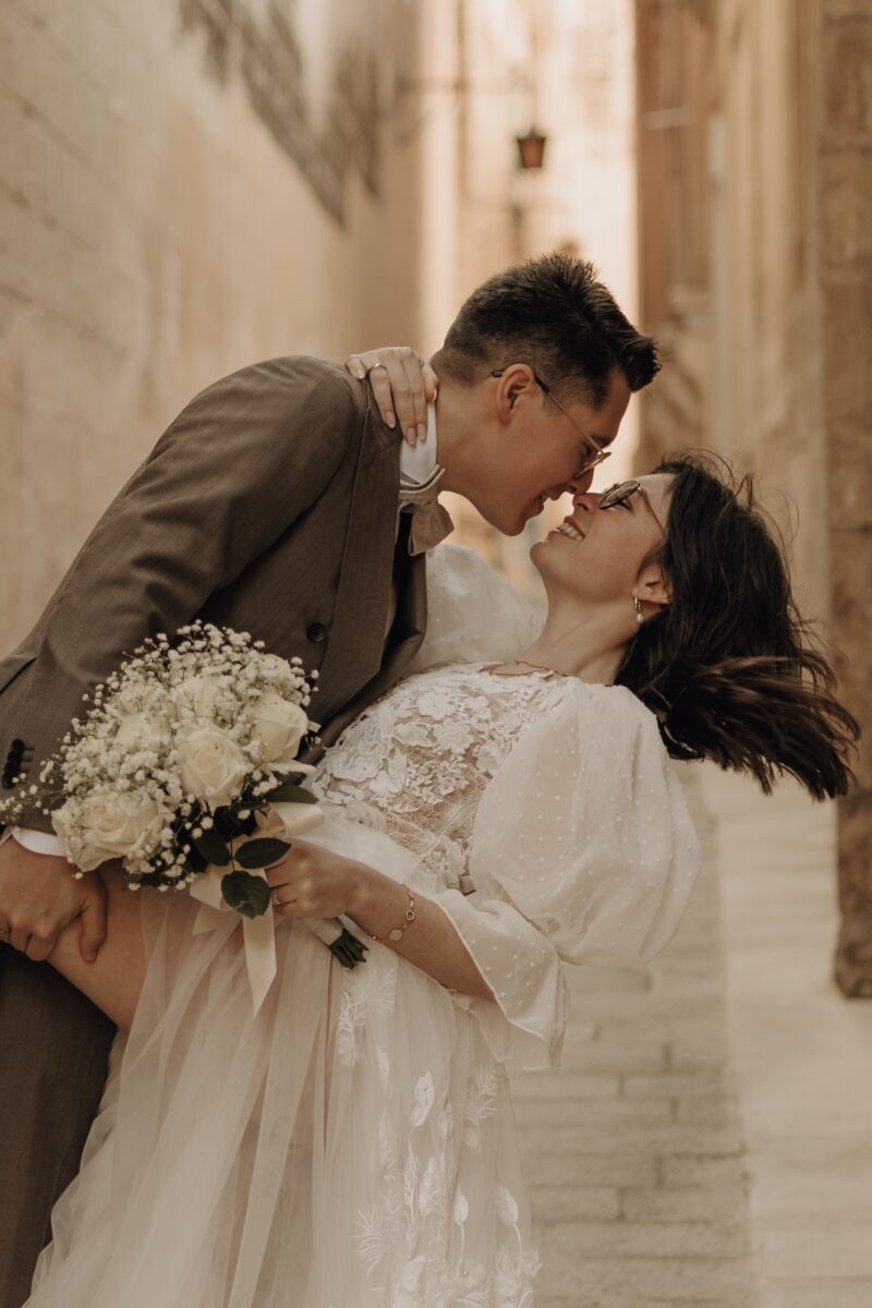 After Wedding Portfolio, Bräutigam lehnt seine Braut in einen Kiss Dip. Beide lächeln sich an. Sie sind sich so nah, dass sich ihre Nasenspitzen berühren