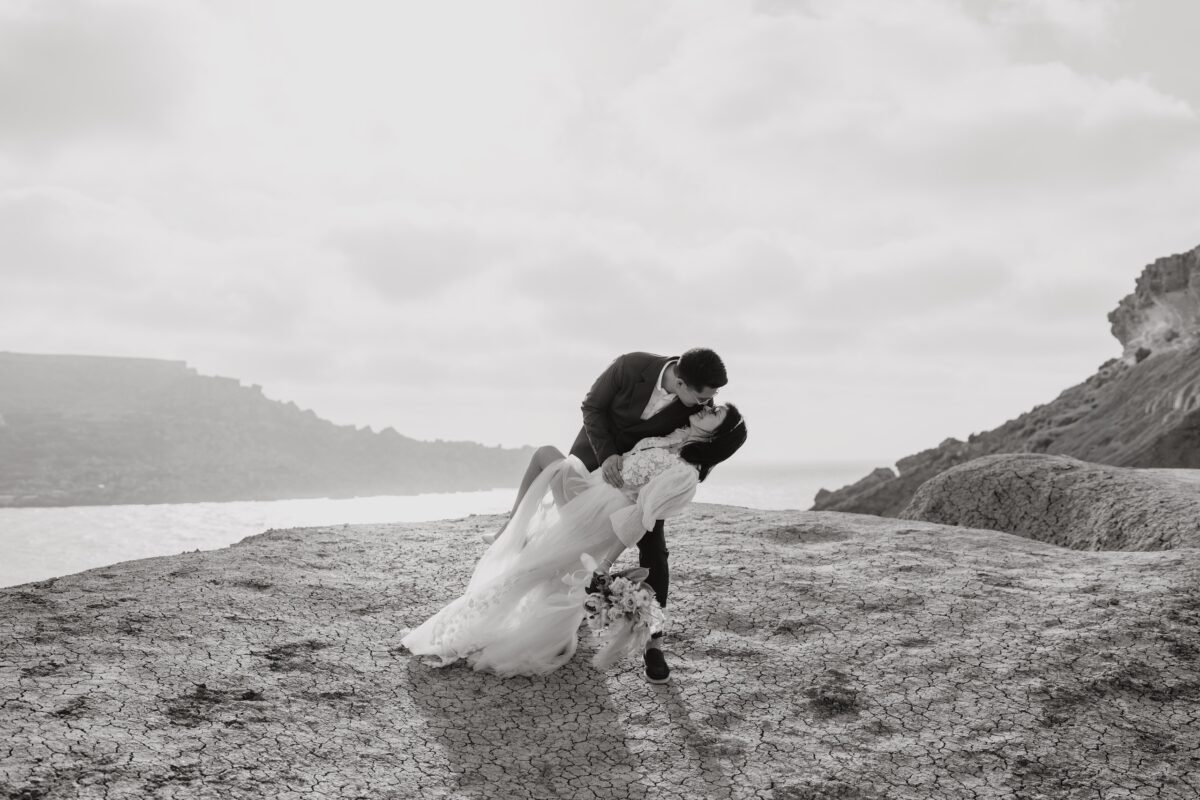 After Wedding Portfolio, der Bräutigam lehnt die Braut in einen Kiss Dip. Beide küssen sich. Die Braut hält ihr Bein angewinkelt.