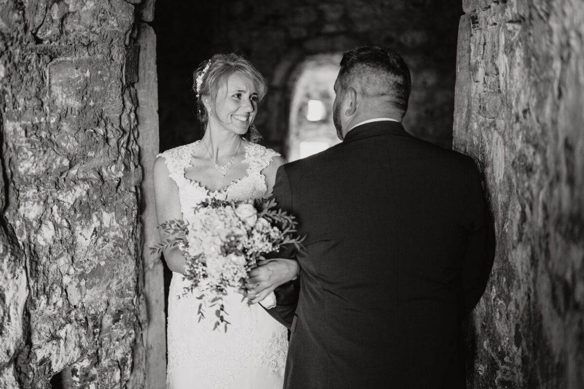 After Wedding Portfolio, Braut steht zu der Kamera, Bräutigam steht mit dem Rücken zur Kamera. Ihre Arme sind ineinander verschränkt und sie schauen sich lächeln an.