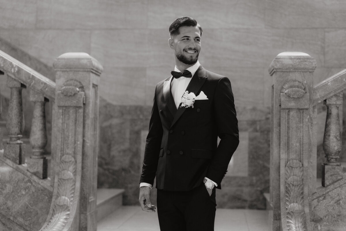 Hochzeitsportfolio, Poräitbild des Bräutigams in schwarz weiss. Er hat die rechte Hand in der Hosentasche und lächelt nach rechts in die Ferne.