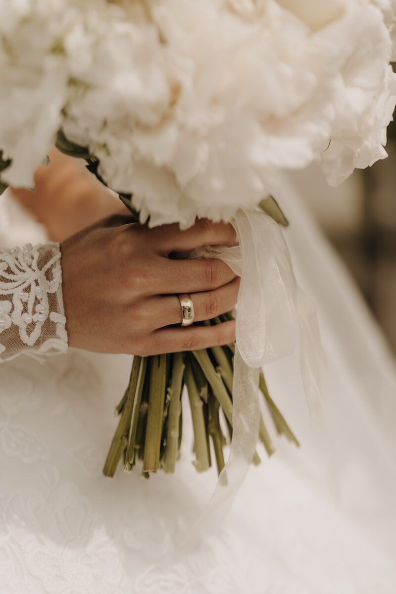 Hochzeitsportfolio, Detailfoto vom Ehering an der Hand, die den Brautstrauß umschließt