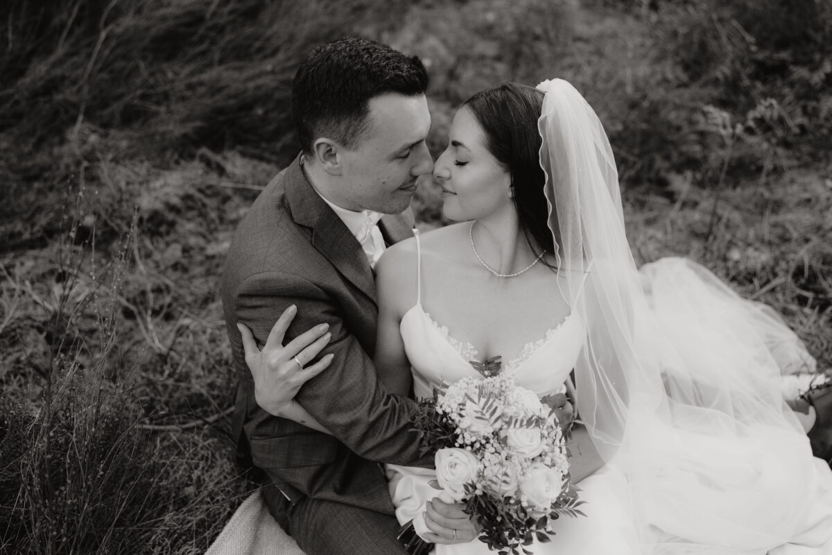 Hochzeitsportfolio, Hochzeitsportfolio, romantisches Brautpaarporträt in Schwarzweiß Brautppar sitzt auf dem Boden zueinander gewandt mit Nasenspitze an Nasenspitze, beide haben die Augen geschlossen | Hochzeitsfotografie Köln