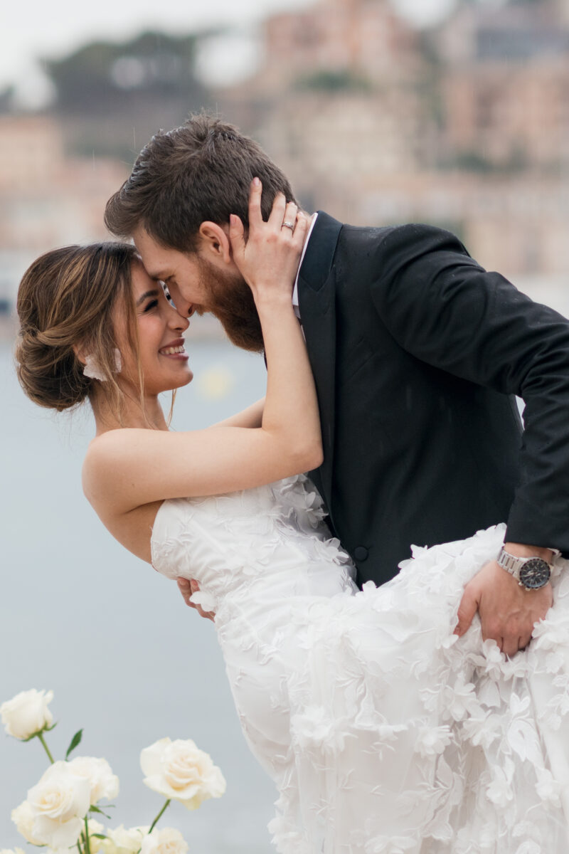 Destination Wedding Portfolio lachendes Hochzeitspaar posiert draußen vor verschwommenem Hintergrund