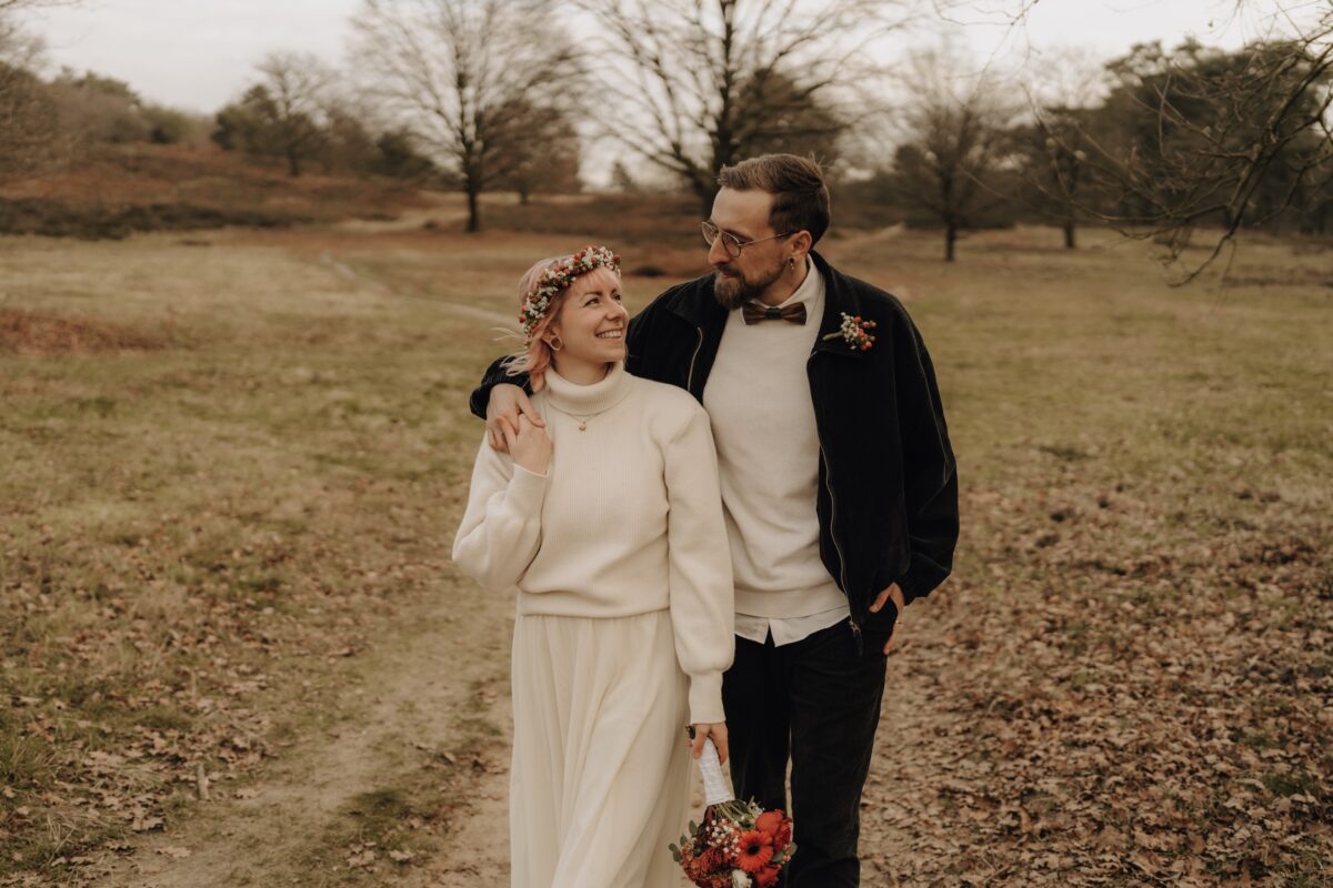 After Wedding Portfolio, Bräutigam hat seinen Arm um die Braut gelegt. Sie hält seine Hand und sie lächeln sich beide an.
