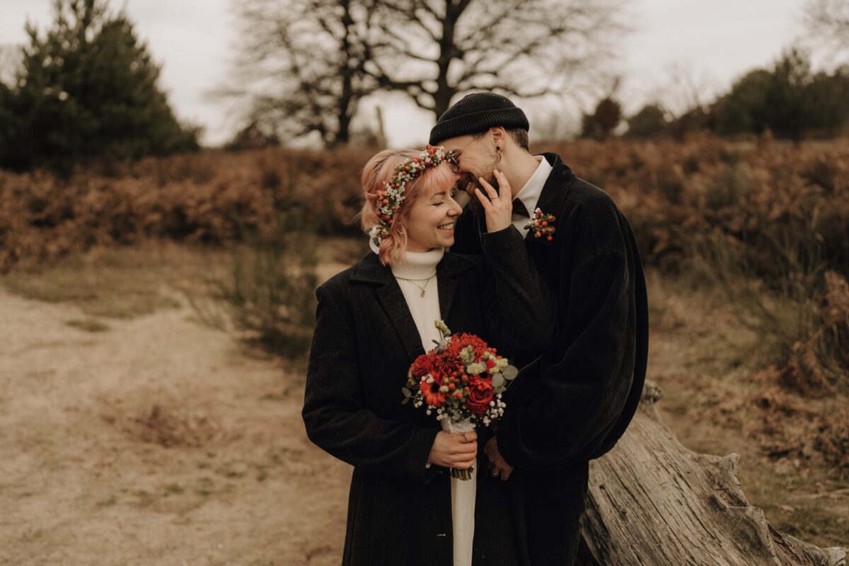 After Wedding Portfolio, Bräutigam flüstert seiner Braut etwas ins Ohr und sie lacht. Braut hat ihre Hand an seiner Wange
