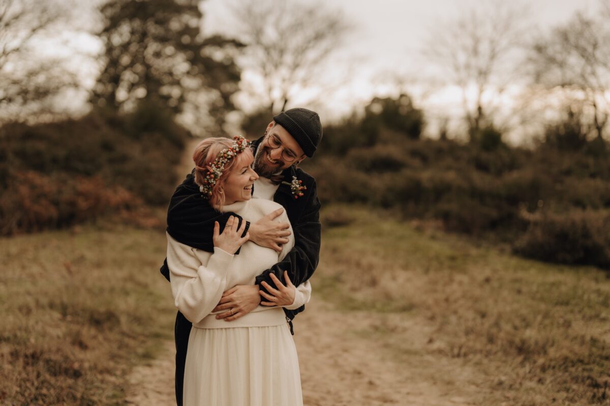 After Wedding Portfolio, Bräutigam umarmt die Braut von hinten und lächelt sie an. Braut lächelt und hält seine Arme.