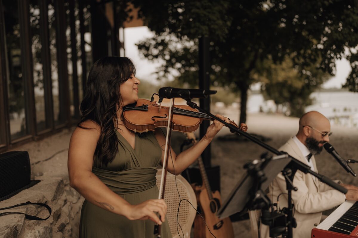 Hochzeitsportfolio, Nahaufnahme von einer Geigerin während sie Geige bei der Hochzeitszeremonie spielt.