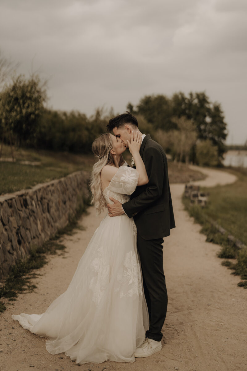 Hochzeitsportfolio, romantisches Brautpaarshooting auf einem Weg im Abendlicht Brautpaar steht gegenüber voneinander und küsst sich | Hochzeitsreportage Köln