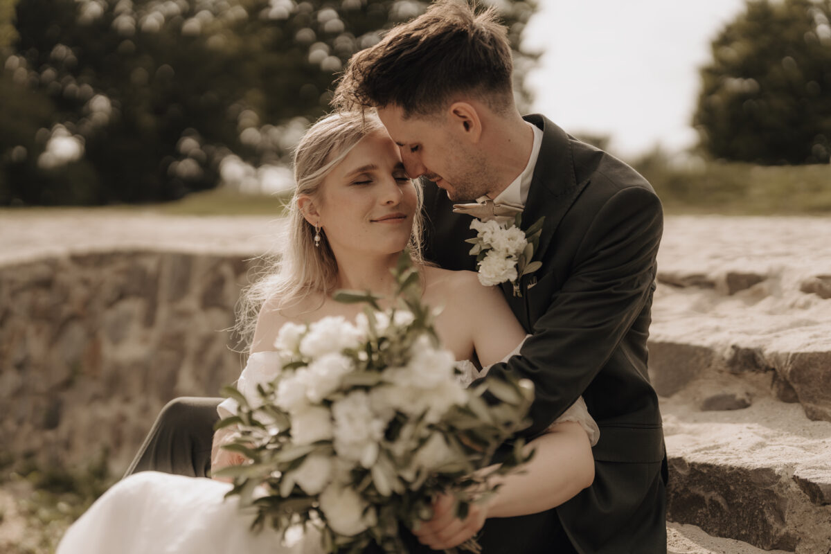 Hochzeitsportfolio, romantisches Brautpaarshooting im warmen Abendlicht, Brautpaar sitzt auf einer Treppe, Bräutigam umarmt dabie die Braut von hinten | Hochzeitsfotografin Köln